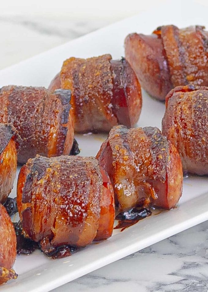close upBourbon Brown Sugar Bacon Wrapped Sausages on white plate
