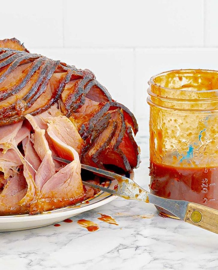 spiral cut Oven Roasted Cranberry Glazed Ham next to cranberry barbecue sauce.