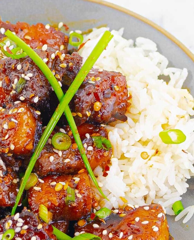 Sticky Chinese Pork Belly with white rice on a gray plate