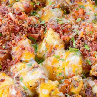 close up of grilled ranch loaded potatoes with melty cheese and parsley and bacon crumbles