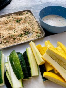 sticks or fries of zucchini and yellow squash next to breading and buttermilk bowl