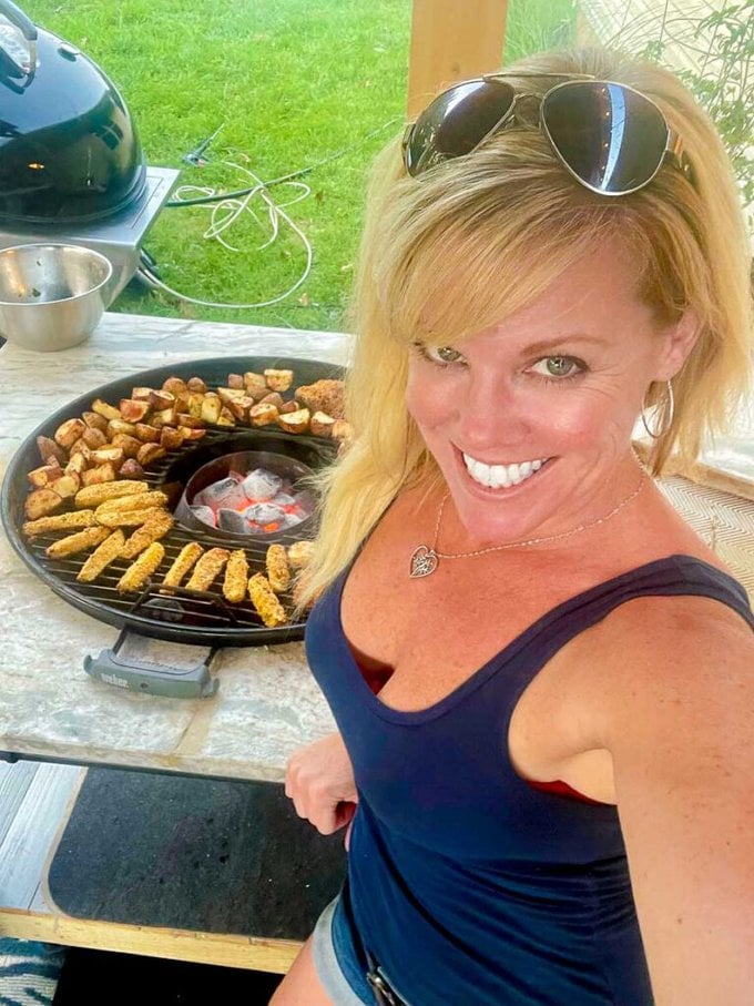 Jennifer standing by the grill while Grilled Panko Parmesan Zucchini Fries and Ranch loading potatoes are cooking.