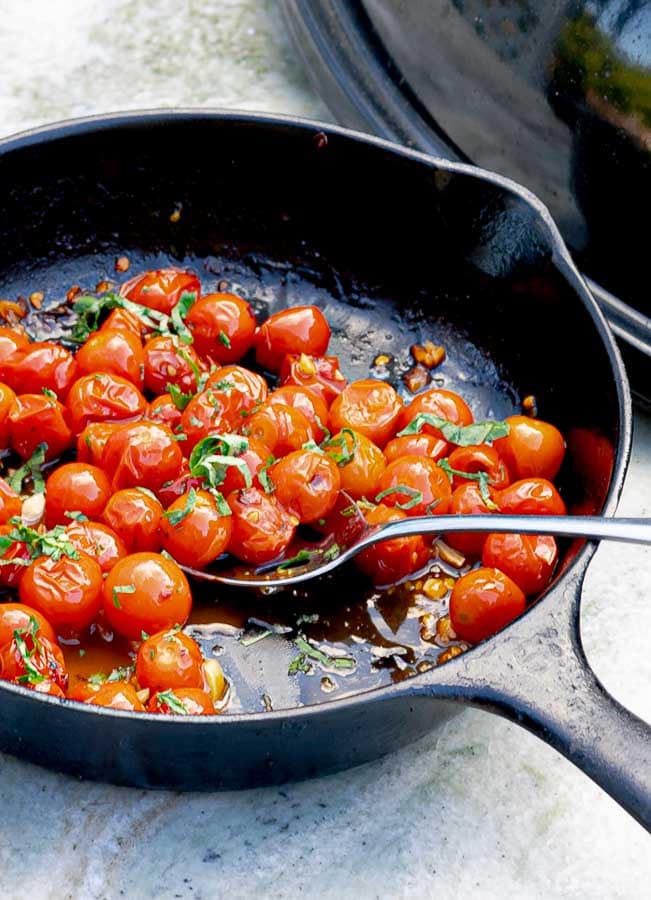blistered cherry tomatoes in a cast iron skillet